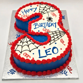 A custom Spider-Man Number cake with red and blue icing, spider webs, a small spider, and “Happy Birthday Leo” message in a playful Spider-Man theme. Contact us for pricing!.