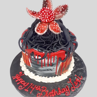 The Stranger Things Flower cake is round with black and red icing, black tendrils, and a Stranger Flower topper. "Happy 14th Birthday Lexi" is written in red on the board—great for kids who love bold designs.