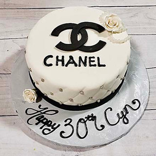 The Chanel Beaded cake features the Chanel logo and “CHANEL” in black, white roses, pearls, and elegant beaded details. The board reads “Happy 30th Cyn” in stylish script. Ideal for specialty birthday celebrations.