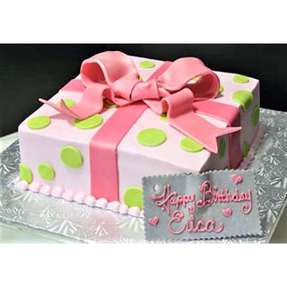 Present Dots is a pink, gift-shaped custom birthday cake decorated with green polka dots and a large pink fondant bow. A plaque says "Happy Birthday Erica" in pink icing, and the cake is set on a silver board.