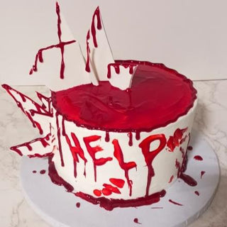 Blood Drip: A white cake with vivid red blood drip icing, edible shards, and "HELP" in red for a dramatic, horror-themed effect. Custom pricing available for this unique and chilling design.