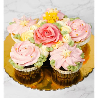 A cluster of cupcakes with pink and cream floral frosting decorates the Cupcake Board on marble, finished with a “Happy Mothers Day” topper—ideal for specialty birthdays and custom cupcake pricing.