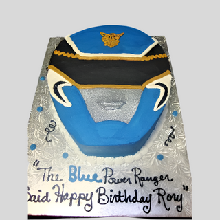The Power Ranger Head cake, designed as a Blue Power Ranger helmet on a silver board, features "Happy Birthday Roy" in black and blue icing—ideal for kids who love character-themed treats.