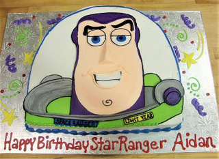 A custom Toy Story Helmet cake with Buzz Lightyear’s face, suit details, and “Happy Birthday Star Ranger Aidan” in red icing on a silver board—perfect for any Toy Story fan.