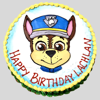 Round custom Chase Drawn cake featuring a dog in a blue police hat. “Happy Birthday Lachlan” is written in red around the edge, with yellow and green icing borders.