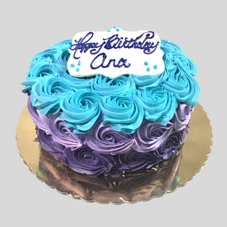 The Rosette Multi is a birthday cake decorated with blue and purple rosette icing, finished with a white "Happy Birthday Ana" plaque in purple script on a gold cake board. Contact us for custom cake pricing.