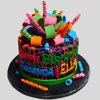 The Neon Birthday cake is a colorful custom cake with vibrant icing, multicolored ribbons, and curly fondant strips. "Happy Birthday" and names are written in bright colors—perfect for a kid's birthday celebration!.