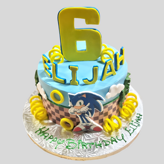 The Sonic Name custom birthday cake features Sonic the Hedgehog, a large yellow number 6, Elijah’s name in yellow letters, and green-iced "Happy Birthday Elijah" on the board.