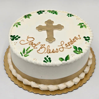 The "Cross Vines" cake is a round white religious cake with green leaf accents, a gold cross and ribbon, and "God Bless Landon" in gold icing. Custom pricing applies. Displayed on a gold scalloped board.