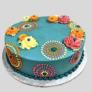 Retro Flowers: A round teal cake decorated with vintage-inspired blooms and detailed dots in yellow, orange, pink, and green—ideal for bridal or engagement celebrations—displayed on a silver floral-patterned cake board.