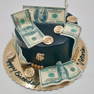 The Money Cake is a round black cake decorated with edible fake $100 bills, gold coins, and pearls. It sits on a gold tray with "Happy Birthday Victoria" written in black icing.