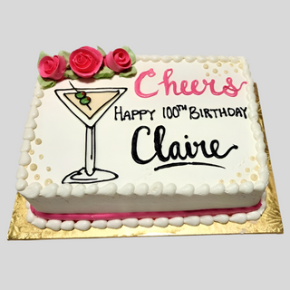 The Martini Cheers cake is a rectangular custom birthday cake for Claire’s 100th, featuring pink roses, a martini glass drawing, “Cheers Happy 100th Birthday Claire” in pink and black icing, with a pink and white border on a gold tray.