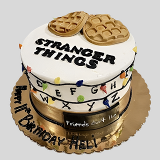 The Stranger Things Lights cake features colorful Christmas lights, STRANGER THINGS lettering, waffles, assorted characters, and the alphabet. It says Friends don't lie and Happy 11th Birthday Heli! on a gold board—perfect for kids.