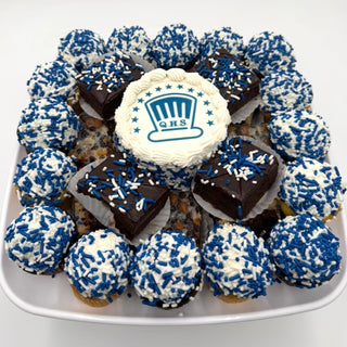 The Celebration Dessert Platter features mini cupcakes and brownies with white frosting, blue and white sprinkles, arranged around a custom "QHS" logo cupcake topped with a blue hat design.