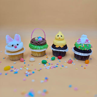 The Easter Cupcakes set features four arranged cupcakes—a bunny, Easter basket, yellow chick, and bunny feet on grass—decorated with colorful candy and sprinkles scattered around them on a peach surface.