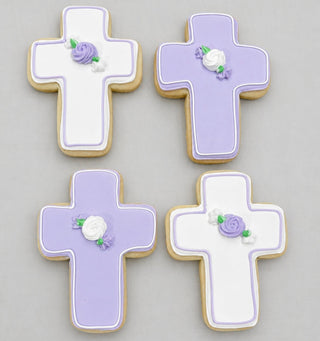 Four Flower Cross Cookies with white and lavender icing, adorned with purple and white roses and green leaves, arranged on a light grey background. Ideal for religious celebrations or as a custom cake companion.