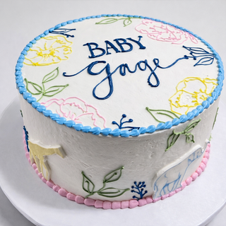The Animal Florals cake is round and white, decorated with colorful flower and leaf outlines, blue and pink borders, "BABY Gage" written in blue icing on top, and outlined animal shapes on the side.