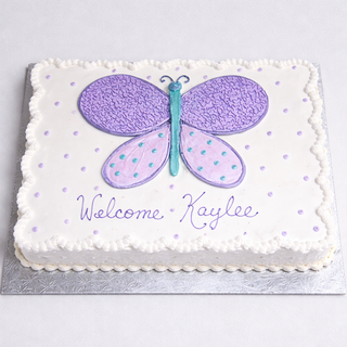 The Butterfly Drawn cake is a rectangular white personalized cake with a large purple and teal butterfly, small purple dots, piped edges, and "Welcome Kaylee" in purple icing.