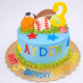 The Sports Birthday cake is blue with colorful stars, sports balls, a big yellow 3, and rainbow "AYDEN" letters. The base says “Happy 3rd Birthday Prince Ayden”—a fun centerpiece for any birthday party!.
