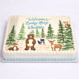 The Woodland Forest cake features hand-painted bears, a fox, a deer, and trees. "Welcome Baby Boy Wheaton" is written in blue icing—an ideal choice for a charming baby shower celebration.