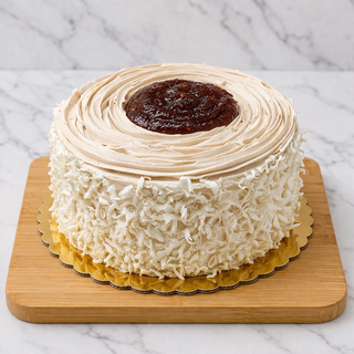 The Mocha Round Layer Cake features layers of raspberry and coconut, covered in light brown mocha frosting with a central swirl of jam and shredded coconut on the sides, beautifully presented on a wooden board.