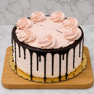 The Chocolate Strawberry Layer Cake features a round chocolate cake with light pink strawberry buttercream, seven piped rosettes, dark chocolate ganache drip, and is presented on a wooden board with a gold base against a marble background.
