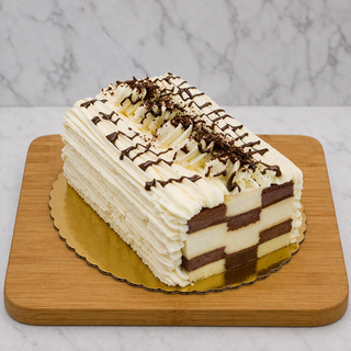 The Checkerboard is a rectangular, layered ice cream cake with chocolate and vanilla layers, topped with piped whipped cream, chocolate drizzle, and chocolate shavings—perfect for any celebration.