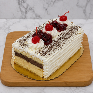 Rum Log: A rectangular cake with vanilla and chocolate Italian custard, white whipped cream frosting, chocolate shavings, whipped cream swirls, red cherries, and cherry filling—beautifully presented on a wooden board with a marble backdrop.