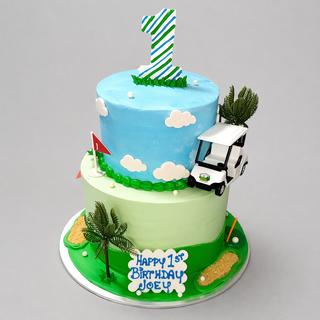 The "Golf Scene" cake is a two-tier design with a striped number one topper, clouds, golf cart, palm trees, and a blue and white plaque reading "Happy 1st Birthday Joey"—ideal for any golf-themed celebration.