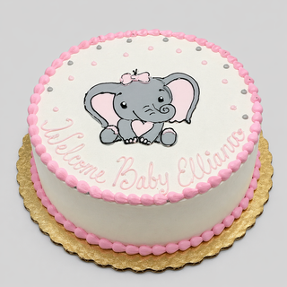 Celebrate with our round Elephant Bow custom cake, featuring pink and white icing, a cute cartoon elephant with a bow, "Welcome Baby Ellianna" in pink script, pink dot borders, and presented on a gold cake board.