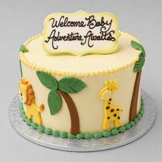 The Safari Palm is a round yellow cake adorned with palm trees, a lion, and a giraffe, topped with a chocolate "Welcome Baby Adventure Awaits" sign. Ideal for baby showers and presented on a silver board.