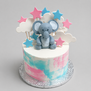 The Elephant Sky cake features pink and blue brushstrokes, a fondant elephant, clouds, and stars on sticks. Displayed on a silver patterned board, it’s the perfect baby shower centerpiece to delight your celebration.