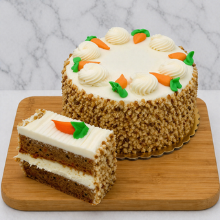 The Carrot Cake with Cream Cheese features two cake layers with white frosting inside, topped with frosting carrots and chopped nuts on the sides. A slice is displayed in front, all arranged on a wooden board.