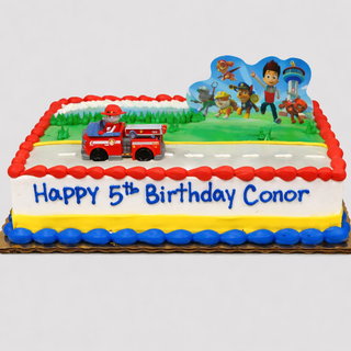 The Paw Patrol Motif cake is a rectangular kids cake with a toy fire truck, scenic backdrop, "Happy 5th Birthday Conor" in blue icing, and decorated with red, white, yellow, and blue festive accents.