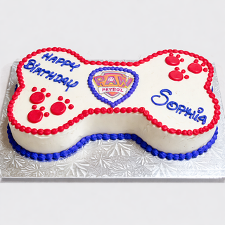 A custom Paw Patrol Bone-shaped birthday cake with red and blue icing, paw prints, the PAW Patrol logo, and "Happy Birthday Sophia" on a silver-patterned board—perfect for kids.