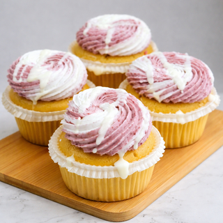 Five White Chocolate Raspberry Cupcakes in white liners, topped with purple and white swirled frosting and white chocolate ganache drizzle, are arranged on a wooden board and stand out beautifully against the light background.