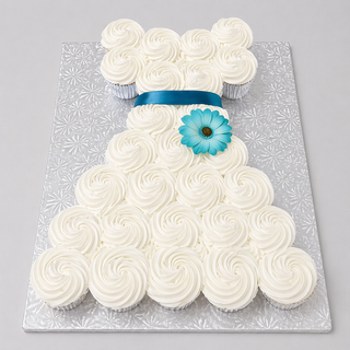The Cupcake Dress features white swirled frosting, a blue ribbon waist, and a blue flower, making it the perfect bridal cupcake centerpiece on a silver patterned board.