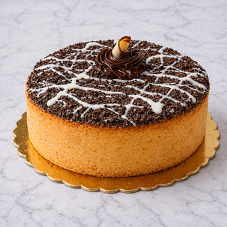 The Oreo Cheesecake is round, set on a gold platter with chocolate crumbs, white icing drizzle, and a swirl of chocolate cream topped with a rolled wafer, all placed on a marble surface.