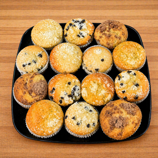 The Mini Muffin Platter features twelve assorted mini muffins, like blueberry, lemon poppyseed, and chocolate chip with various toppings, arranged neatly on a black square plate atop a wooden surface.