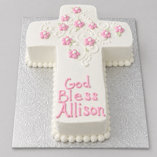The Daisy Cross is a custom religious cake, shaped like a cross with pink and white flower decorations and "God Bless Allison" in pink icing, presented on a silver patterned board.
