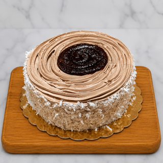 The Mocha Round Layer Cake is a round white cake with light brown mocha frosting and coconut shavings on the sides, topped with a swirl of chocolate frosting and glossy raspberry preserves, displayed on a wooden board with a marble background.