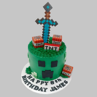 The Minecraft Scene birthday cake features a round design with pixelated sword and TNT blocks on top, green Creeper face icing, and "Happy 8th Birthday James" written on the white base.