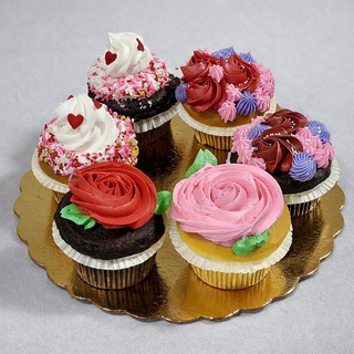 The Valentines Cupcakes set includes six cupcakes on a gold platter, each topped with red, pink, white, and purple rose-like swirls and heart-shaped sprinkles for a festive look.
