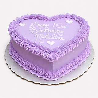 The Heart Ruffles cake is a heart-shaped lavender birthday cake with ruffled edges, piped borders, "Happy 15th Birthday Madeline" in icing, and decorated with small white hearts.